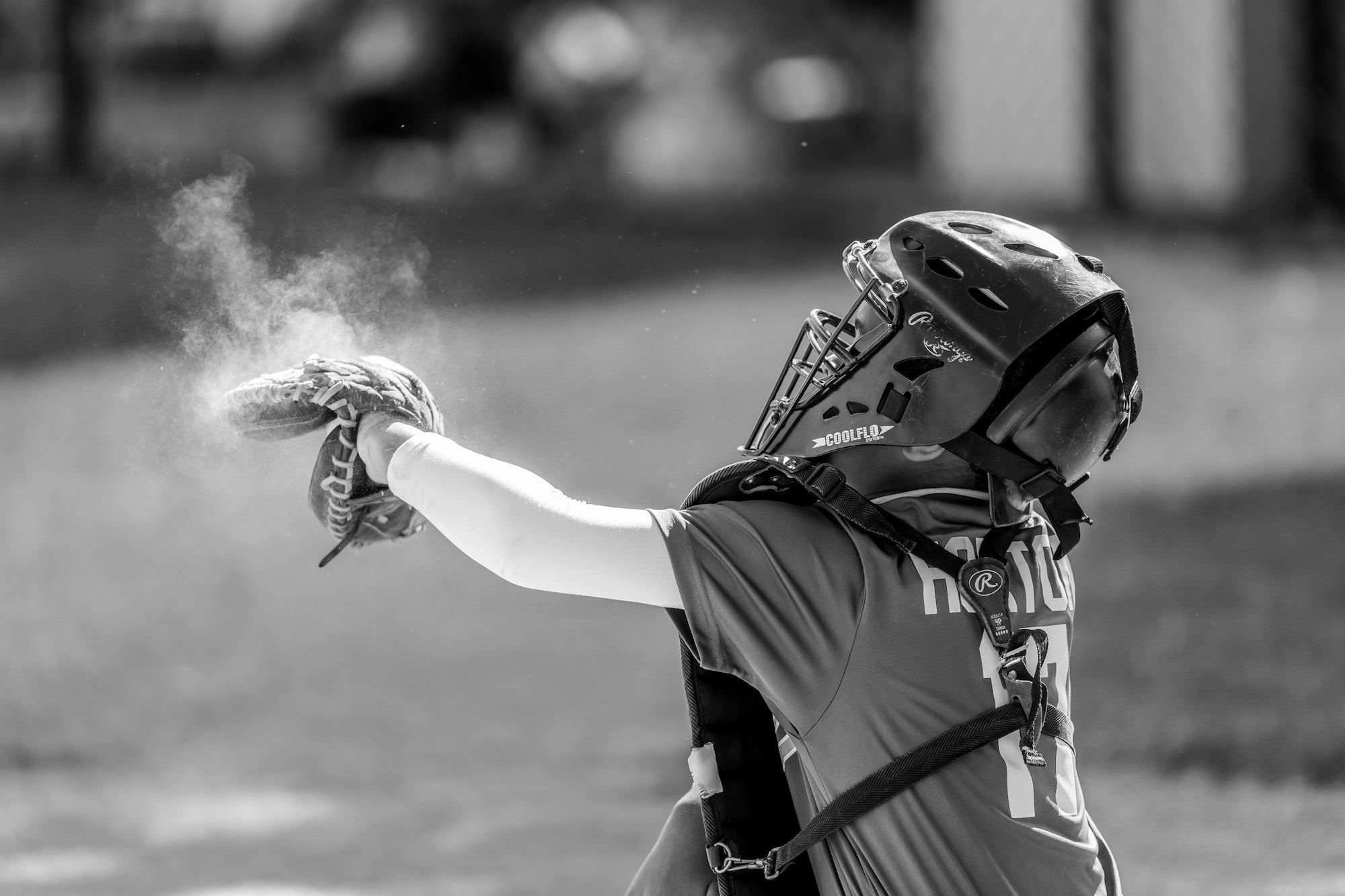 Youth baseball catcher extends a gloved hand as chalk dust puffs, black-and-white action. Youth baseball catcher extends a gloved hand as chalk dust puffs, black-and-white action.