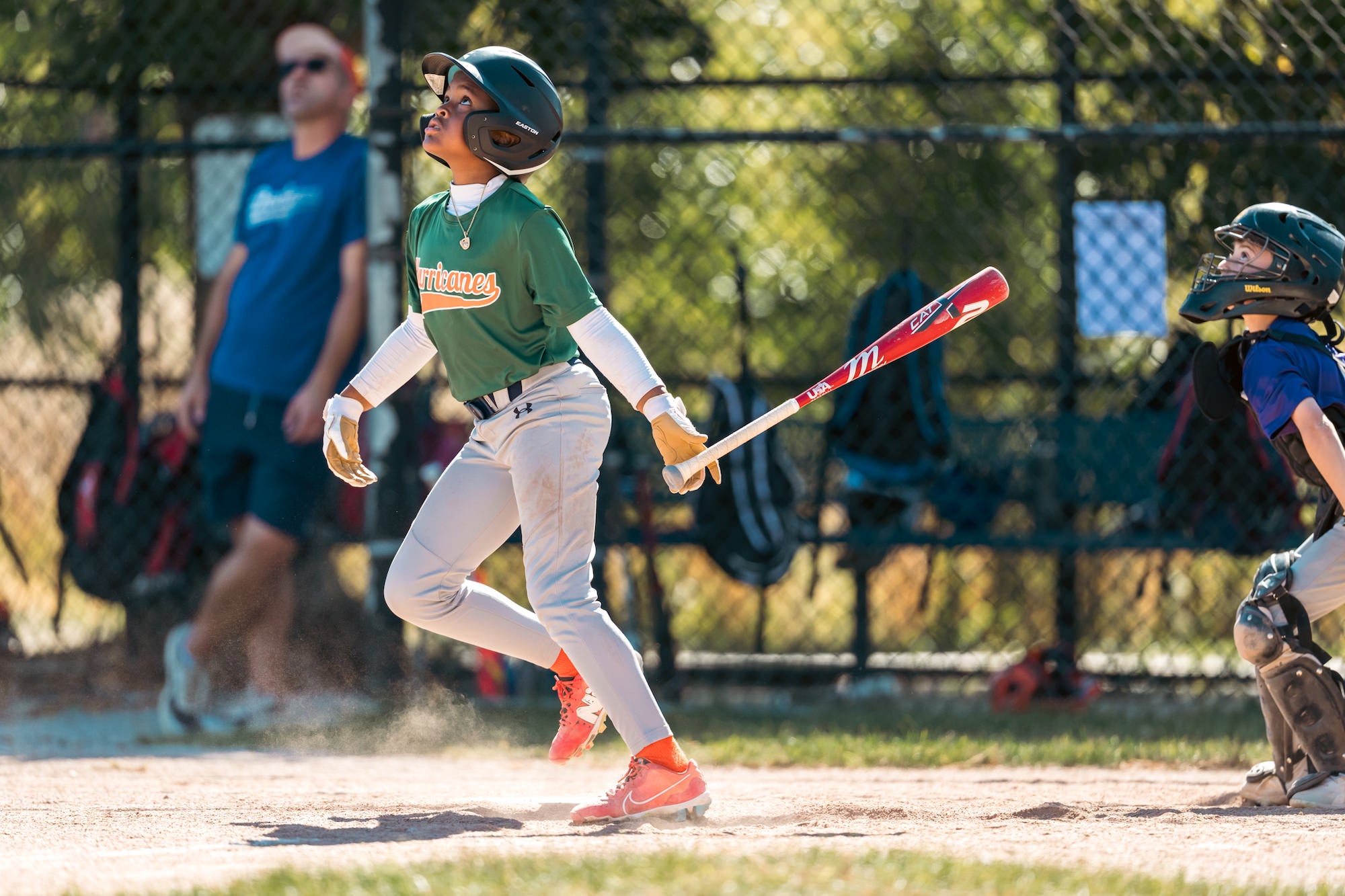 Batter watches a high pop-up near home plate, bat released, catcher and dust visible. Batter watches a high pop-up near home plate, bat released, catcher and dust visible.