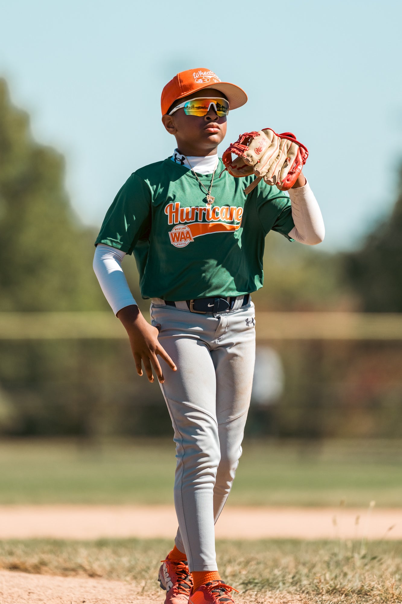 Infielder in green jersey waits between plays, glove raised, soft background bokeh. Infielder in green jersey waits between plays, glove raised, soft background bokeh.