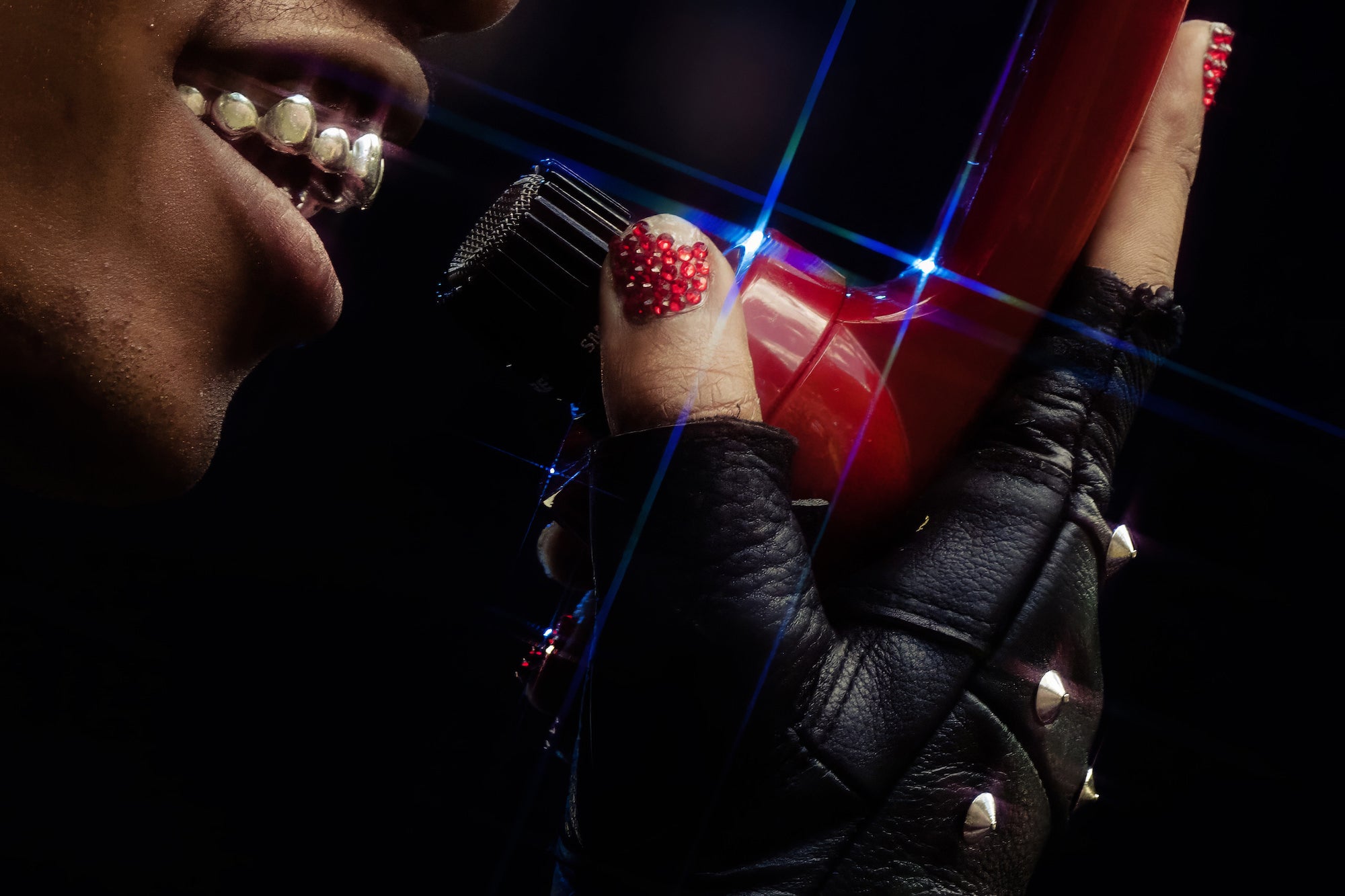 Extreme close-up of studded glove holding mic; glittered nail art sparkling. Extreme close-up of studded glove holding mic; glittered nail art sparkling.