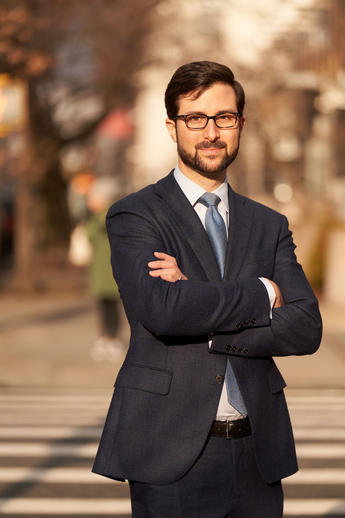 Environmental portrait of a man in a suit with arms crossed, standing outside. Environmental portrait of a man in a suit with arms crossed, standing outside.