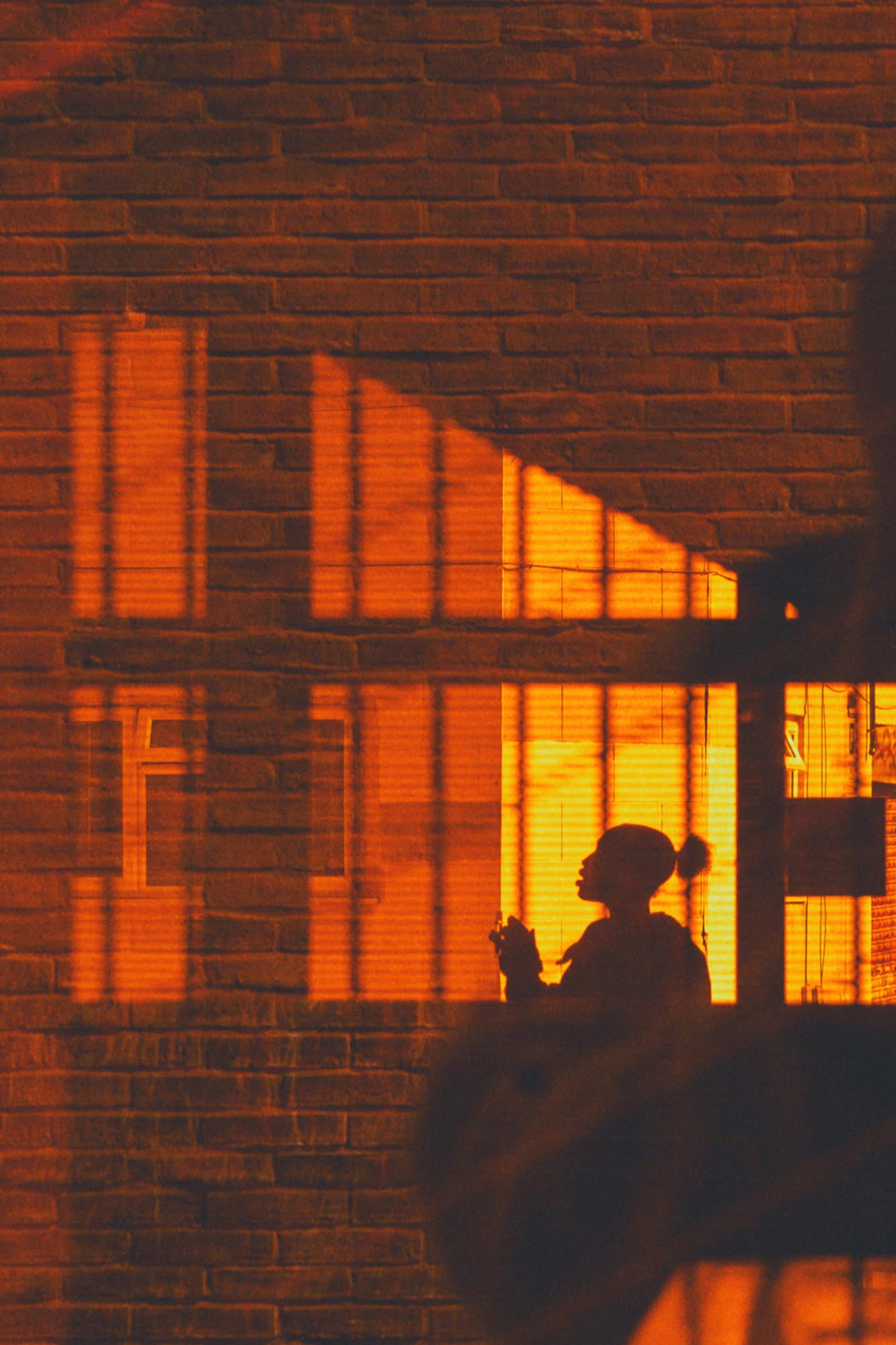 Warm window light casting graphic shadows on brick with a clean silhouette. Warm window light casting graphic shadows on brick with a clean silhouette.