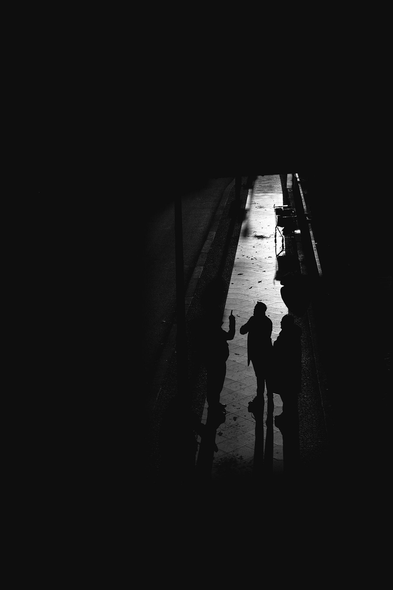 Three silhouettes conversing in a narrow alley, high-contrast black and white. Three silhouettes conversing in a narrow alley, high-contrast black and white.